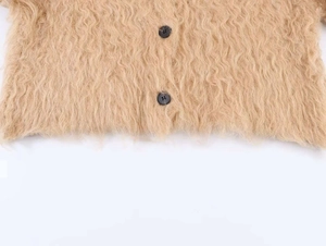 Detailed close-up of khaki plush knit cardigan fabric with fuzzy texture and black buttons