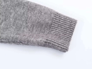 Detail of ribbed cuff on a soft grey knit sweater showing fine fabric texture