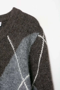 Detailaufnahme von braunem Strickpullover mit Rautenmuster und geripptem Rundhalsausschnitt