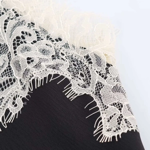 Close-up of black satin fabric with intricate cream eyelash lace trim detail