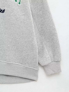 Detail of grey knit sweatshirt featuring vintage college letters and ribbed elastic cuffs