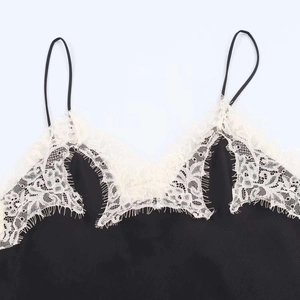 Macro detail of the elegant black satin camisole featuring delicate white lace neckline