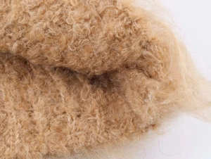Close-up macro shot of soft camel shearling fabric texture for V-neck sweater knitwear