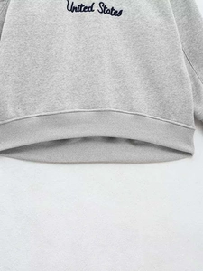 Close-up of ribbed hem and United States lettering on gray sweatshirt fabric
