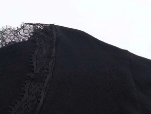 Detail of elegant black knitwear featuring delicate floral lace trim and eyelash edges