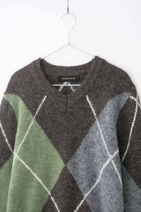 Detailed close-up of V-neck argyle knit sweater in brown and green with fuzzy texture