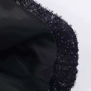 Dettaglio del tessuto tweed nero con paillettes e fodera in maglia a costine fini