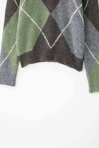 Detail of argyle knit sweater with ribbed cuffs in green, brown, and grey pattern