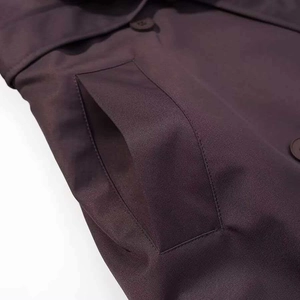 Gros plan détaillé du tissu du trench-coat kaki avec coutures de précision et bouton mat