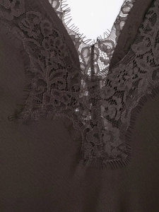 Detailed macro view of the deep brown satin dress with intricate black eyelash lace trim