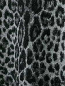 Close-up of soft leopard print knit fabric showing detailed animal pattern texture