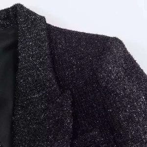 Dettaglio della spalla e del rever del blazer in tweed nero con fili metallici argentati