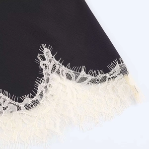 Lace trim detail of a black satin camisole featuring delicate cream eyelash lace edges