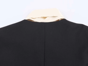 Detailed close-up of a minimalist black blazer with a white contrast collar and fine stitching