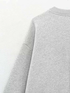 Detail of grey knitted sweater showing ribbed crew neck and soft fabric texture