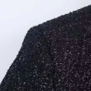 Dettaglio del tessuto in tweed nero con fili metallici argentati e fibre intrecciate