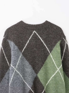 Close-up detail of vintage diamond pattern knit sweater with green and grey patches
