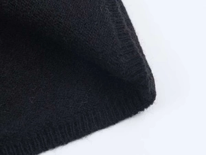 Close-up of black knitted fabric showing fine texture and lace stitching details