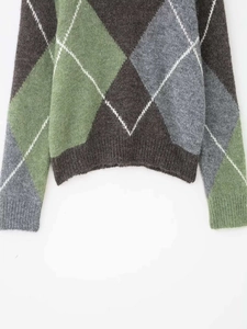 Detail of argyle knit sweater hem and ribbed cuffs in sage green and grey tones