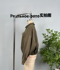 Detail of olive green bomber jacket featuring pleats at the hem and cargo chest pockets