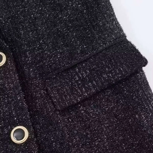 Dettaglio macro del tessuto tweed nero con fili metallici argentati e bottoni dorati