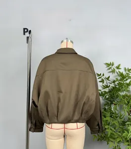 Detail view of the back seams and metal snap cuffs on a tan bomber jacket