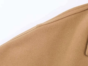 Detailed close-up of camel wool coat fabric showing premium stitching and texture