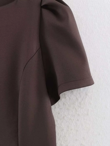 Détail de la manche bouffante structurée sur une robe unie marron foncé ajustée