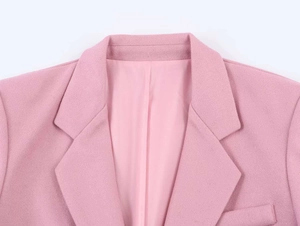 Close-up of pink wool-like blazer showing lapel collar, shoulder detail and fabric texture