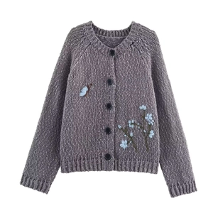 Detail of grey knit cardigan featuring delicate blue butterfly and flower embroidery