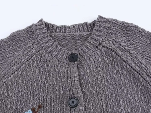 Detailed view of grey knit cardigan featuring floral embroidery and dark buttons
