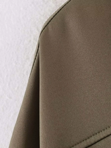 Close-up detail of military green bomber jacket with pleated hem and premium stitching