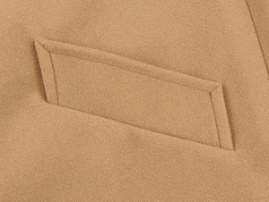 Close-up of camel wool coat detail showing premium stitching and flap pocket texture