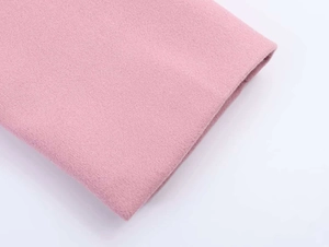 Detailed macro shot of premium pink wool fabric texture and clean hem stitching on coat