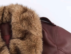 Detail of burgundy leather jacket featuring a thick textured brown faux fur collar