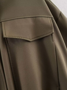 Close-up of olive green bomber jacket pocket with clean stitching and durable twill fabric