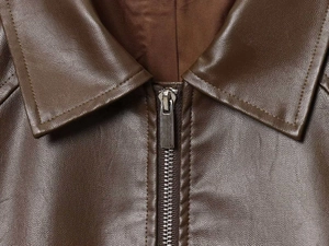 Detailed close-up of dark brown leather jacket collar with metallic zipper and stitching