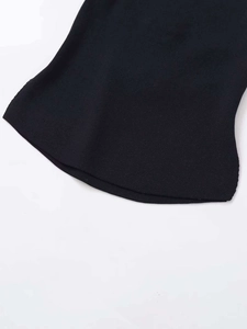 Close-up of black knitted vest showing fine fabric texture and curved hemline detail