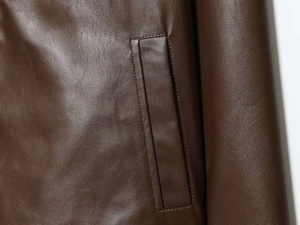 Detailed view of dark brown leather jacket featuring a sleek welt pocket and fine stitching