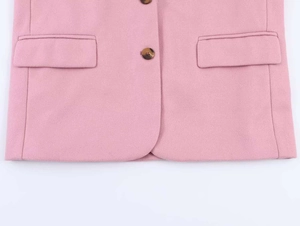 Detail of pink wool blazer with flap pockets and textured amber buttons on hem