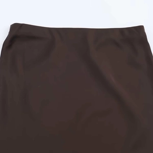 Dettaglio del girovita di una gonna in raso marrone scuro con cuciture minimaliste piatte