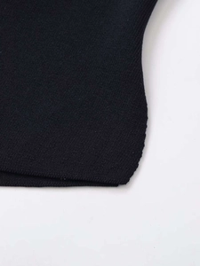 Close-up of the black ribbed knit fabric and high-quality stitching on the garment edge