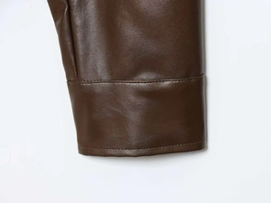Detailed macro view of dark brown faux leather texture with neat stitching on hem