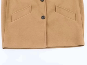 Detail view of camel wool coat featuring dark buttons and symmetrical welt pockets