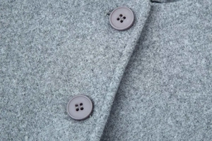Detail of grey textured wool fabric with stylish purple round buttons on an overcoat