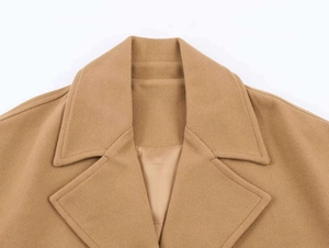Detail of classic camel wool coat showing sharp lapel collar and precise stitching