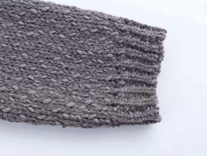 Detailed close-up of grey knit sweater cuff with intricate thick-knit honeycomb texture