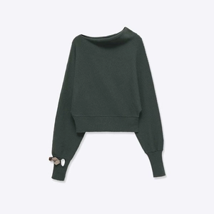 Detail of dark green knit top showing asymmetric neckline and ribbed texture
