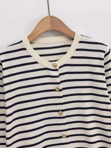 Close-up of fine knit stripes and decorative embossed gold buttons on a round neck cardigan