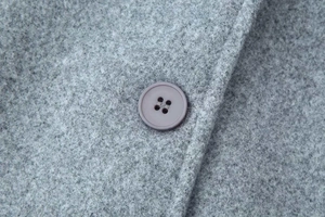 Detailed macro view of grey wool fabric texture and matching four-hole round button finish